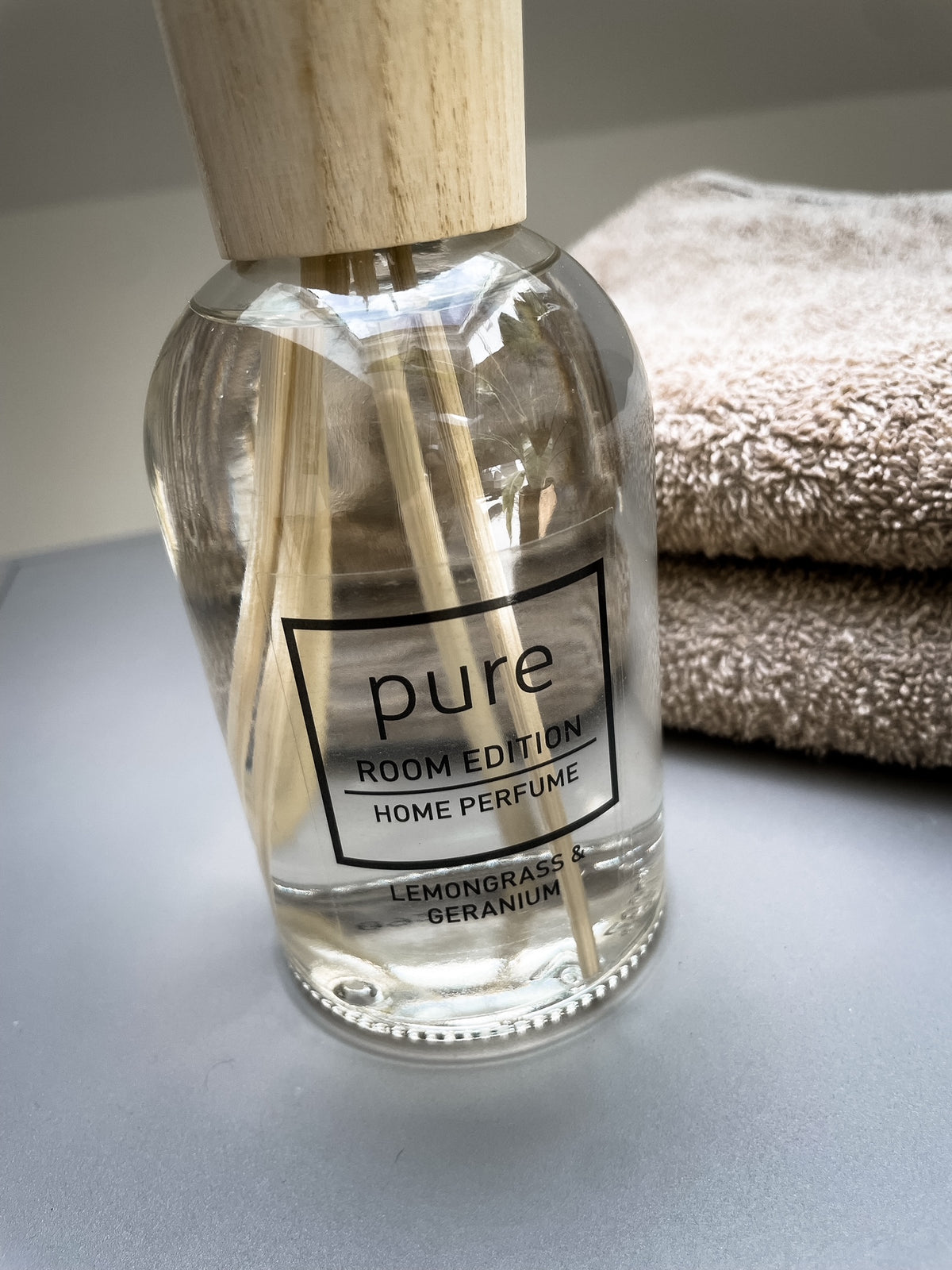 PURE Glasflakon im Detail neben Handtüchern